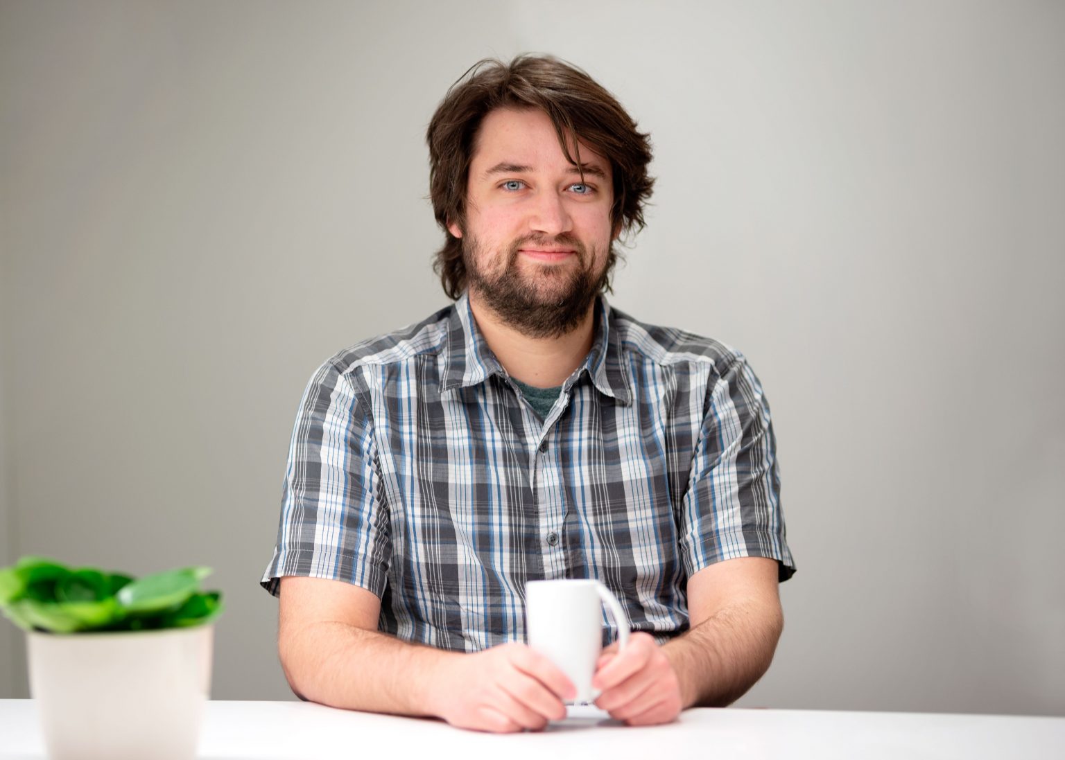 Mathias, vår systemutvikler, som står med kaffekopp og smiler. Foto